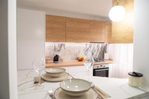 a kitchen with two plates and wine glasses on a counter at Scandinavia Apartment 2 in Piatra Neamţ
