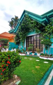 a blue house with flowers and plants in a yard at Affordable Spacious Bedroom & Bathroom near DVO Airport in Davao City