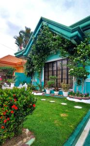 una casa azul con flores y plantas en un patio en Affordable Spacious Bedroom & Bathroom near DVO Airport en Davao