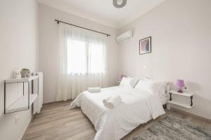 um quarto branco com uma cama branca e uma janela em City Nexus Family 2BD residence Kolonos, Athens em Atenas