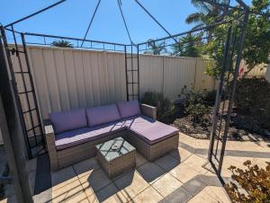 eine Verandaschaukel mit einem lila Sofa und einem Tisch in der Unterkunft Lake Estate Stay in Perth