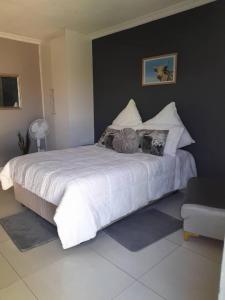 1 dormitorio con 1 cama grande con sábanas y almohadas blancas en Kangumine Self Catering Units, en Okakarara