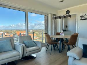 a living room with a table and chairs and a large window at Koksijde Zeedijk Res Manh in Koksijde