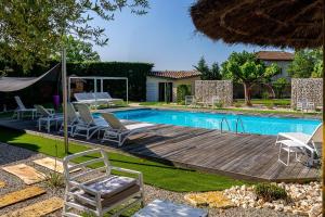 a swimming pool with chairs and a wooden deck next to a swimming pool at Hôtel Karène in Saint-Paul-lès-Romans