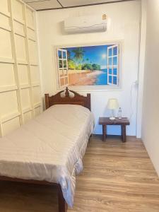 ein Schlafzimmer mit einem Bett und einem Bild von einem Strand in der Unterkunft เพชรบูรณ์ แอทโฮม in Phetchabun