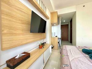 een slaapkamer met een flatscreen-tv aan de muur bij Aesthetic Studio Unit in Bluhen Tower in Batam Center