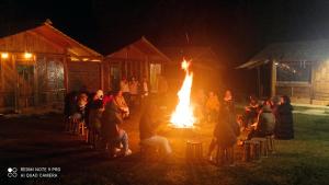 un grupo de personas sentadas alrededor de un fuego por la noche en Homestay Chu Vang en Phong Thổ