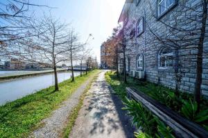 eine unbefestigte Straße neben einem Gebäude neben einem Fluss in der Unterkunft Alps Garden B&B in Wujie