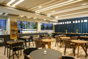 un ristorante con tavoli e sedie e un bar di Sadot Hotel Ben Gurion Airport - an Atlas Boutique Hotel ad Assaf Harofeh