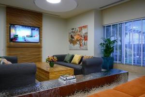 a living room with a couch and a tv at Sadot Hotel Ben Gurion Airport - an Atlas Boutique Hotel in Assaf Harofeh +24 photos