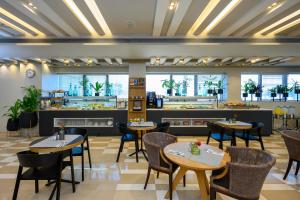 a restaurant with tables and chairs and a counter at Sadot Hotel Ben Gurion Airport - an Atlas Boutique Hotel in Assaf Harofeh
