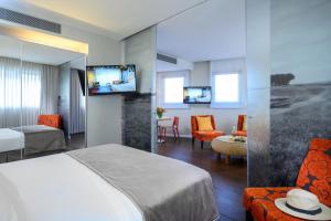 una camera d'albergo con letto e soggiorno di Sadot Hotel Ben Gurion Airport - an Atlas Boutique Hotel ad Assaf Harofeh