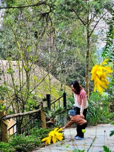 una mujer jugando con flores amarillas en un jardín en Sapa Jungle Homestay en Sa Pa