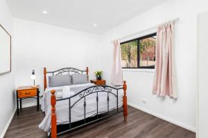 1 dormitorio con cama y ventana en 4Bed Modern Oasis by Train Station, en Wyong