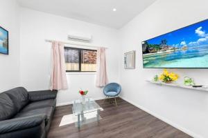 sala de estar con sofá y TV en la pared en 4Bed Modern Oasis by Train Station, en Wyong