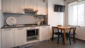 une cuisine avec des placards en bois et une table avec des chaises dans l'établissement Fiori sull'Acqua Apartments, à Peschiera del Garda
