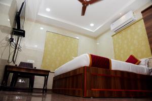 a bedroom with a bed and a desk and a television at Sri Vishnu Residency in Sriperumbudur