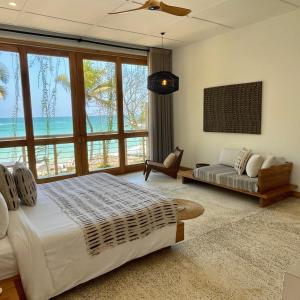 1 dormitorio con cama, sofá y ventanas en La Playa Beach Club, en Hiriketiya