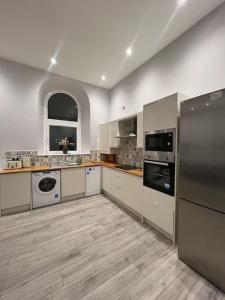 a large kitchen with stainless steel appliances and wooden floors at Welsh Getaway Apartment - Town Centre in Merthyr Tydfil