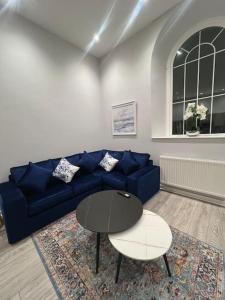 ein Wohnzimmer mit einem blauen Sofa und einem Tisch in der Unterkunft Welsh Getaway Apartment - Town Centre in Merthyr Tydfil