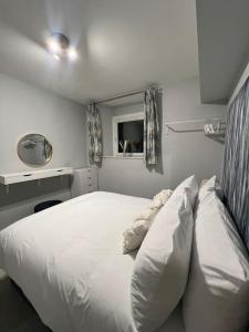 Schlafzimmer mit einem weißen Bett und einem Spiegel in der Unterkunft Welsh Getaway Apartment - Town Centre in Merthyr Tydfil