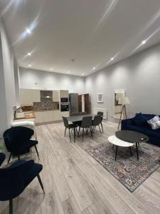 ein Wohnzimmer mit Tischen und Stühlen sowie eine Küche in der Unterkunft Welsh Getaway Apartment - Town Centre in Merthyr Tydfil