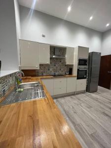 a large kitchen with white cabinets and a wooden floor at Welsh Getaway Apartment - Town Centre in Merthyr Tydfil