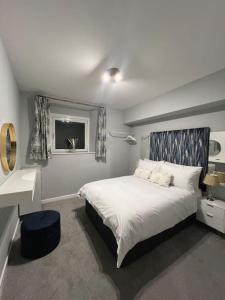 a bedroom with a white bed and a window at Welsh Getaway Apartment - Town Centre in Merthyr Tydfil