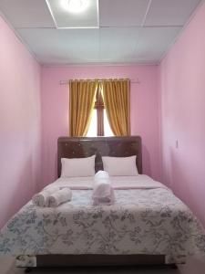 a bedroom with a bed with pink walls and a window at Alice Villa2 in Tuk Tuk