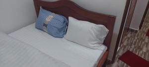 een bed met een houten hoofdeinde en 2 kussens bij RUbuto ABNB in Kigali