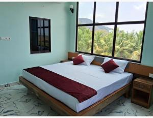 a bedroom with a large bed with two windows at Hotel Gridhakuta International in Rājgīr