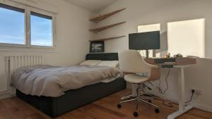 Schlafzimmer mit einem Bett, einem Schreibtisch und einem Stuhl in der Unterkunft Appartement lumineux et cosy avec balcon - 3P in Les Lilas