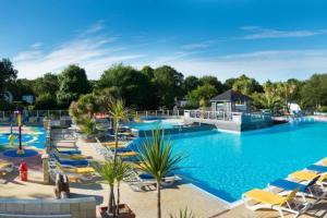 a large swimming pool with lounge chairs and a resort at Bungalow Pont- aven in Pont-Aven