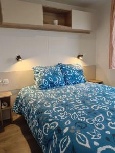 a bedroom with a blue and white bed with pillows at Bungalow Pont- aven in Pont-Aven