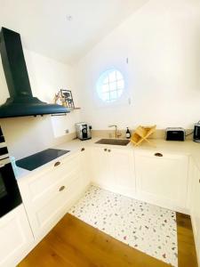 a kitchen with white cabinets and a sink and a window at Villa Libellules lac et mer in Soorts-Hossegor