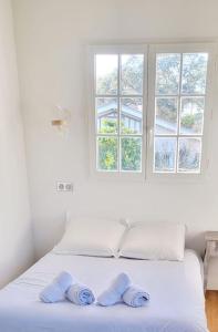 a white bedroom with a bed with two towels on it at Villa Libellules lac et mer in Soorts-Hossegor