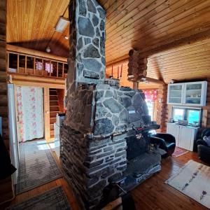 una chimenea de piedra en la sala de estar de una cabaña de madera en Helmi Äärelä en Vuotso