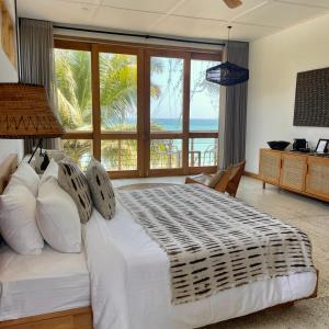 1 dormitorio con cama blanca y vistas al océano en La Playa Beach Club, en Hiriketiya