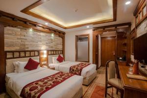 a hotel room with two beds and a desk at Hotel Manang in Kathmandu