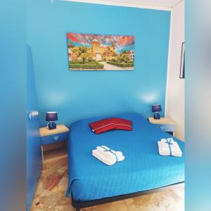 Un dormitorio azul con una cama con toallas. en B&B D'Amico87, en Bagheria
