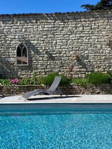 a stone wall and a pool with a chair next to it at VILLA DEL RE 3 face à la piscine in La Flotte