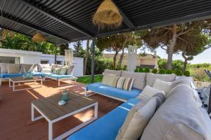 eine Terrasse mit blauen und weißen Sofas und einem Tisch in der Unterkunft VILLA SIEMPRE DOMINGO MARBELLA in Marbella