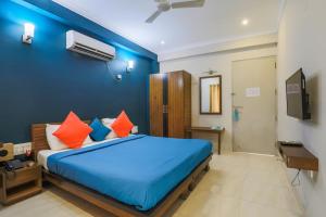 a bedroom with a large blue bed with orange pillows at Hotel Wedlock 39 in Gurgaon