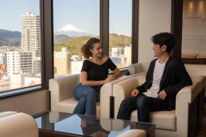 un hombre y una mujer sentados en sillas en una habitación en Hotel Associa Shizuoka, en Shizuoka