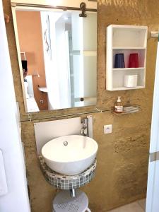 ein Bad mit einem Waschbecken und einem Spiegel in der Unterkunft RAVISSANT STUDIO in Uzès