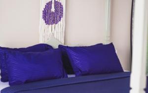 ein Bett mit lila Kissen und ein Gemälde an der Wand in der Unterkunft Lost Planet Midigama in Galle