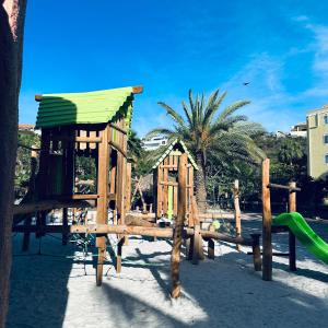 um parque infantil de madeira com um escorrega e uma estrutura de brincar em Villa at Blue Bay Resort with stunning view em Willemstad