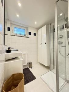 a white bathroom with a shower and a sink at Auszeit in idyllischer Lage in Bad Urach