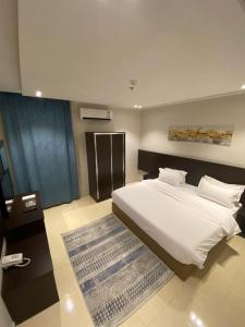 a bedroom with a large white bed and a television at Zmroud Al-Morouj in Yanbu