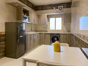 a kitchen with a white table and a refrigerator at شقق زمرد المروج للشقق المخدومة in Yanbu